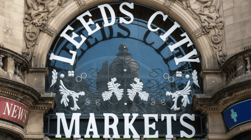 Shoppers browse independent food stalls at Leeds Kirkgate Market historic retail destination